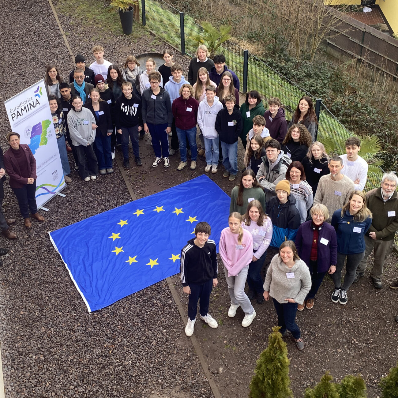 Gruppenbild der PAMINA-Schülerkonferenz. In der Mitte aller Teilnehmenden eine EU-Flagge.