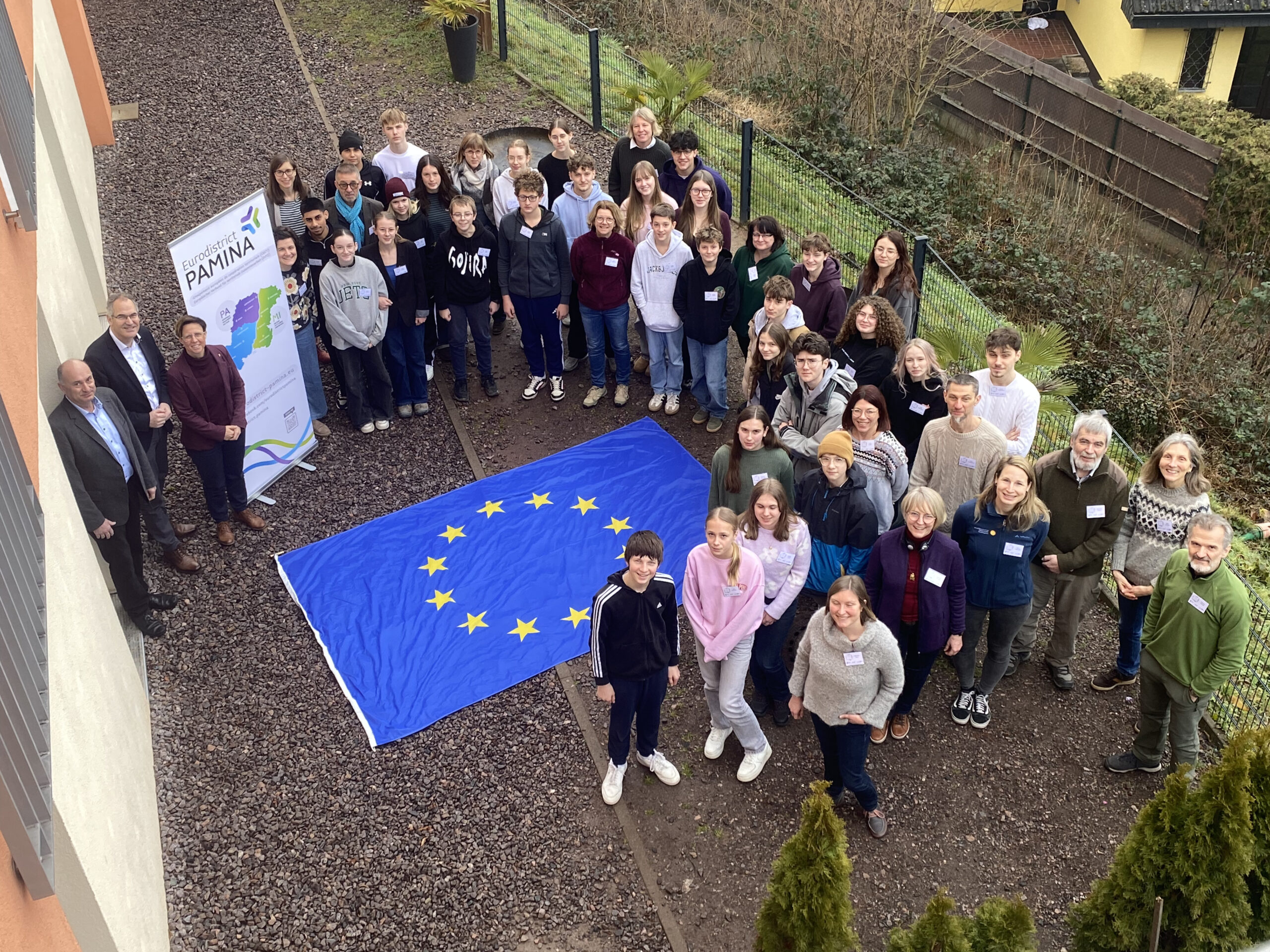 Gruppenbild der PAMINA-Schülerkonferenz. In der Mitte aller Teilnehmenden eine EU-Flagge.
